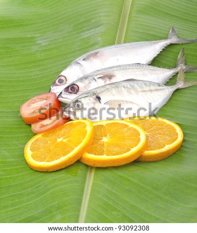 Fresh fish with lemon and tomato stacked on banana leaf.