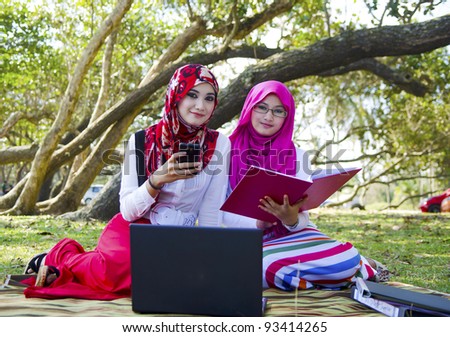 Pretty young Muslim woman in study group while surfing the internet as reference.