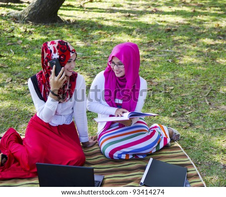 Two young Muslim lady in discussed while answer a phone voice call.