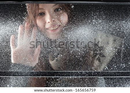 young happy girl behind snow window dark