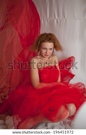 beautiful girl in red dress on white and red background  posing sitting