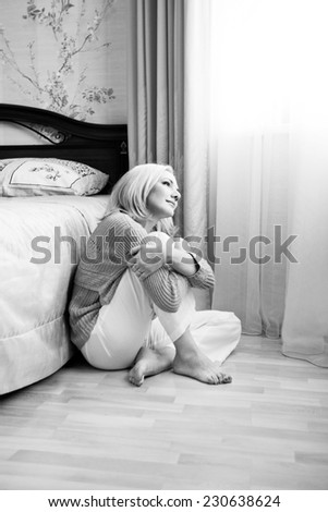Black and white girl sitting on the floor cross-legged in the interior
