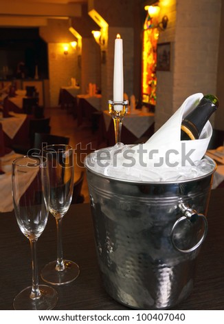 glasses of champagne and a bucket with a candle and a rose on the background of the restaurant