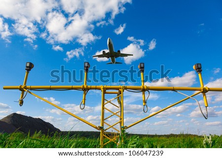 white jet passenger aircraft with the gear against the blue sky and landing lights and green grass, view from below