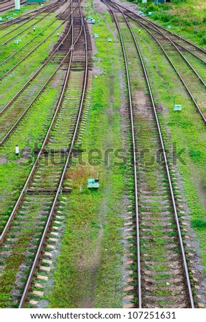 fork in the road and railway tracks on a background of green grass