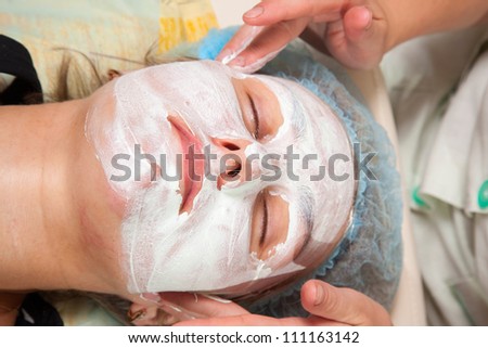 application of a cosmetic mask on the face of young woman at the beautician