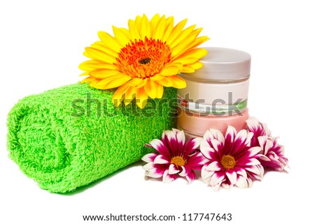 green towel jars of cream gerbera and chrysanthemum isolated on white background