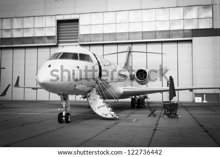 white private jet and open ladder at the airport on a background cloudy sky