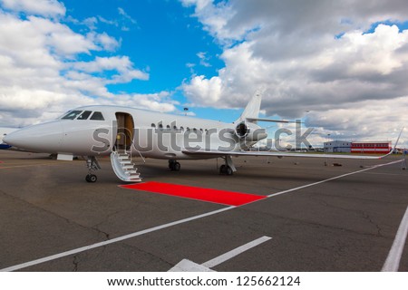 White reactive jet, the front landing gear and gangways on blue sky and clouds