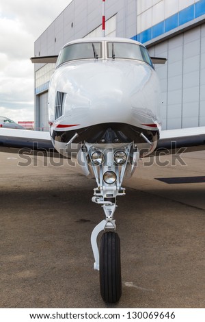 White reactive private jet, the front landing gear on blue sky and clouds