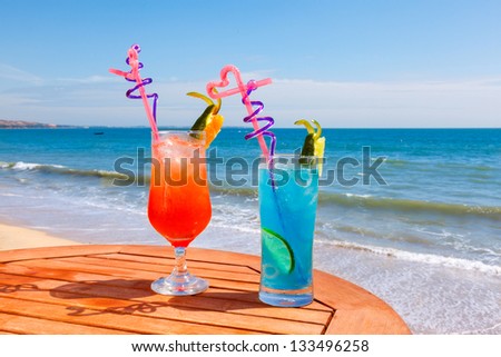 Sunrise cocktail and cocktail blue lagoon on the table on the background of blue sea and sky