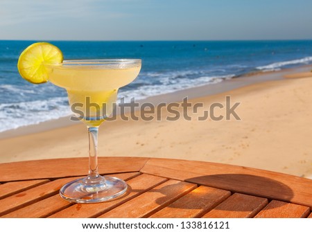 daiquiri cocktail with ice on wooden table against the background of sea and sky