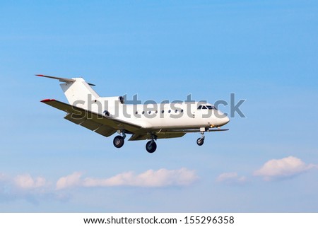 view from below on the white private jet with the gear against the blue sky