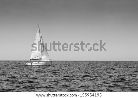 beautiful sailboat with a white sail, blue Mediterranean sea ocean horizon, black and white
