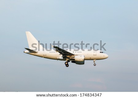 view from below on the white jet passenger aircraft with the gear against the blue sky