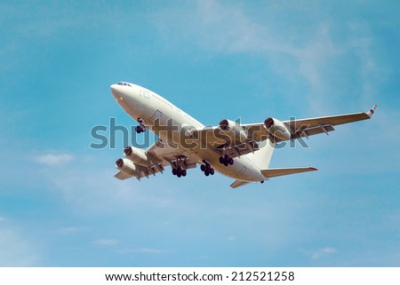 view from below on the white jet passenger aircraft with the gear on the background the blue sky