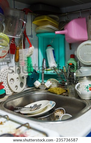 Pile of dirty dishes in sink and counter top, mess in the kitchen