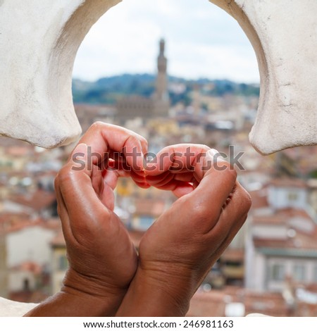 views over the rooftops of Florence through the fence with ornament on bell tower in Florence and palm heart-shaped.