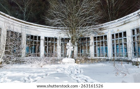 old abandoned Soviet statue and building under the snow at night