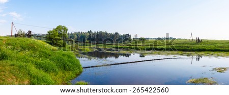 Pedestrian suspension bridge of steel and wood over the river, summer in Russia