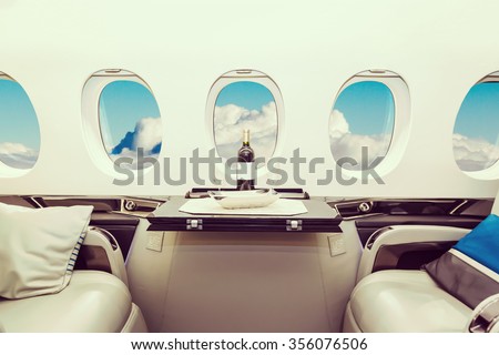 Luxury interior in bright colors of genuine leather in the business jet, sky and clouds through the porthole