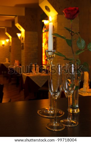 glasses of champagne with a candle and a rose on the background of the restaurant