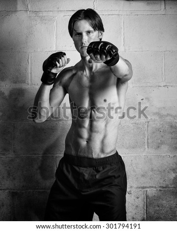 Young adult martial artist in front of a concrete block wall. Black and white.