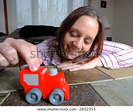 A young woman playing with a red toy truck.