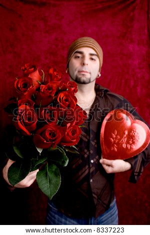 A young man with a heart-shaped box of chocolates and a dozen red roses.