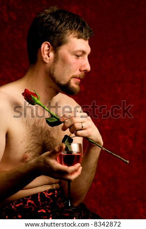 A young man with a single red rose and a glass of wine.