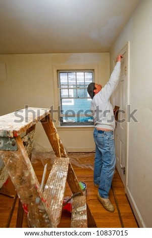 A man painting a white wall with a brush