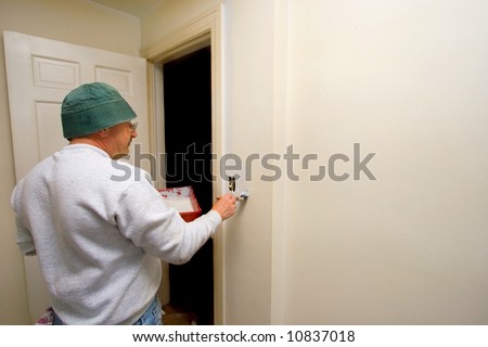 A man painting a white wall with a brush