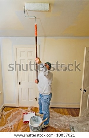 A man painting a white ceiling with a roller