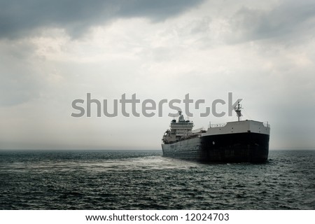 A large commercial vessel departs from harbor after a storm.