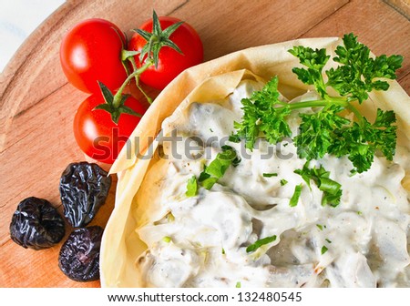 Chicken and mushroom cream salad served in a pastry basket with fresh tomato and dried plums