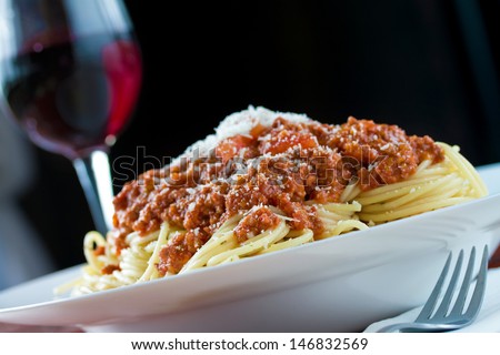 Ragu alla bolognese a complex sauce with spaghetti pasta and glass of red wine