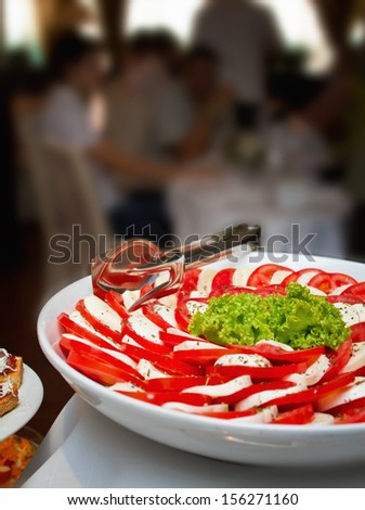 Caprese salad close up shot on a wedding banquet table with blurred people in background