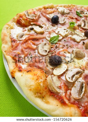 Rustic thin crust pizza with tomato sauce, mozzarella, ham, mushrooms, olives and fresh basil