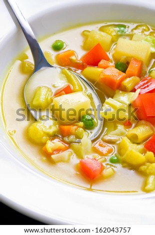 Close up shot of vegan soup with visible vegetable chunks and spoon