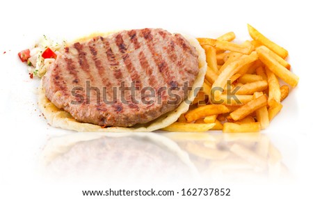Traditional serbian burger patty (pljeskavica) served with some fresh fries and visible grill marks on a homemade pita bred