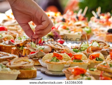 Candid shot of human taking canape party catering. Outdoor shot.
