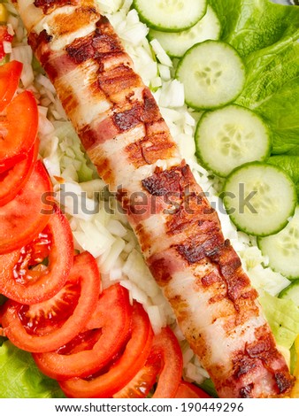Very rich and long bacon wrapped kebab or dog served with plenty of vegetable salad