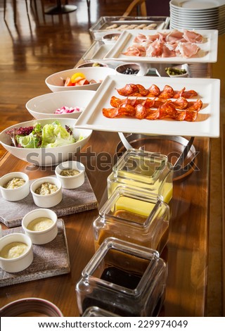 Stylish hotel breakfast buffet with jam, honey, butter, salad and cold cuts.