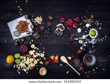 Raw cakes, fresh fruits and nuts for desserts beautifully arranged on a black wooden table/Raw cakes and fresh fruits