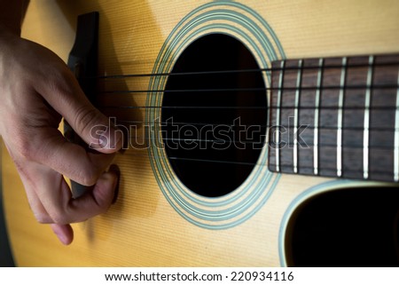 Playing acoustic guitar with a guitar pick.