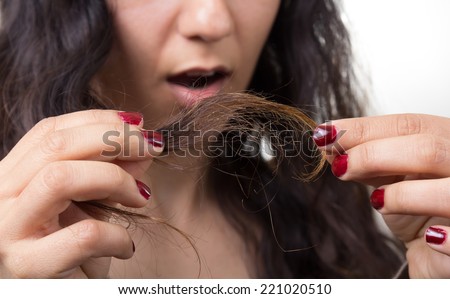 Girl looking at damaged splitting ends of hair.