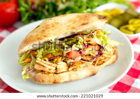 Delicious chicken sandwich doner kebab with some raw vegetables served on a table.