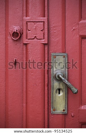 Door handle with an old double wood door painted red color