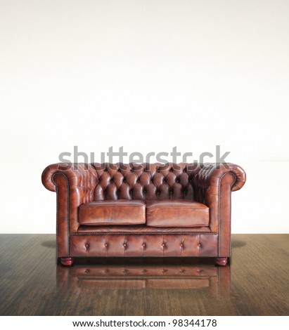 Classic Brown leather sofa and old wood background.
