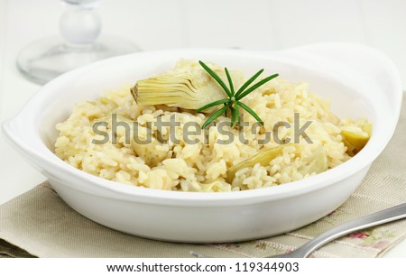 Italian risotto with artichoke hearts and fresh rosemary served in a white plate